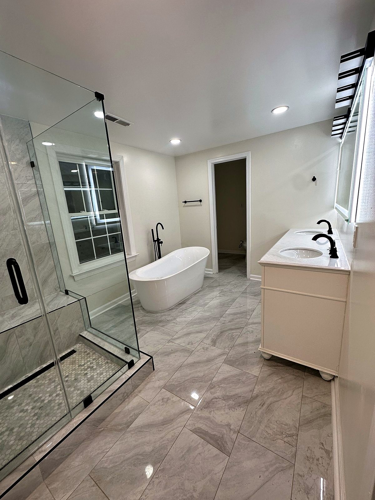 Primary bathroom with frameless glass shower, freestanding tub, and matte black fixtures